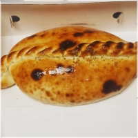 Gevulde pizza met kipdonervlees, kaas, tomaten, champignons, paprika, ui en oregano